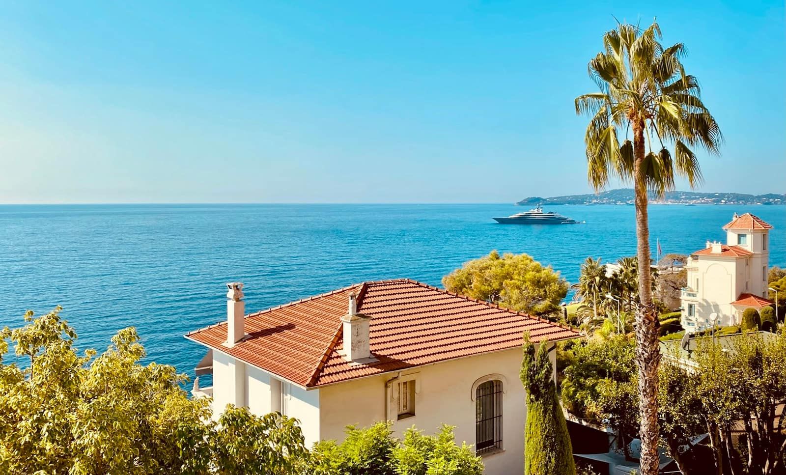 Maison aux toits de tuiles rouges entourée de jardins au-dessus de la mer