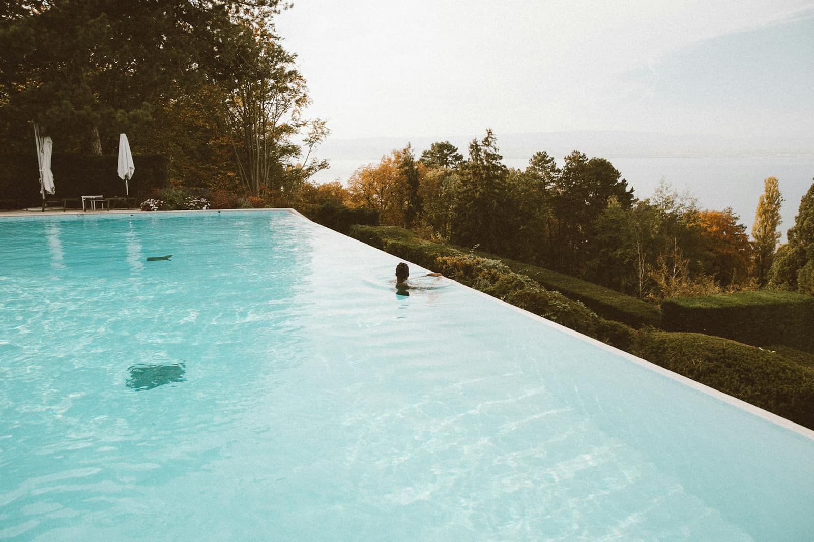 Piscine à débordement dominant une colline arborée
